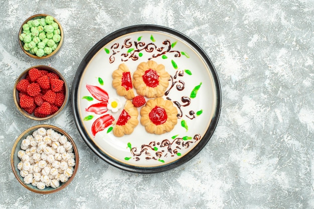 Top view delicious cookies with red jelly and candies on light white background biscuit cake cookie sweet tea