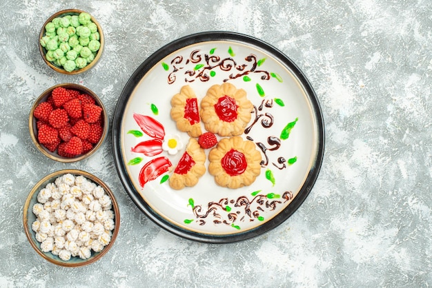 Top view delicious cookies with red jelly and candies on white background biscuit cake cookie sweet tea