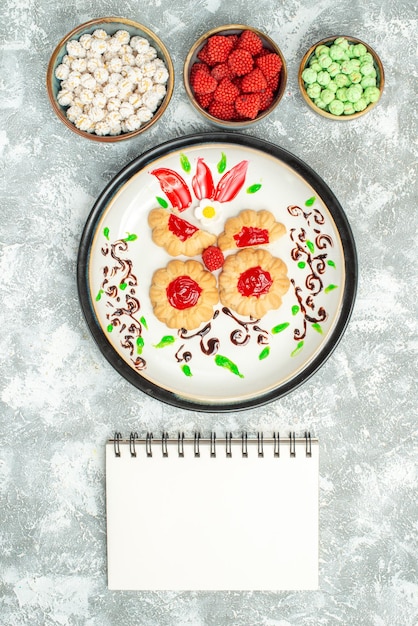 Free photo top view delicious cookies with red jelly and candies on white background biscuit cake cookies sweet tea