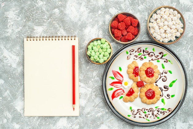 Top view delicious cookies with red jelly and candies on white background biscuit cake cookies sweet