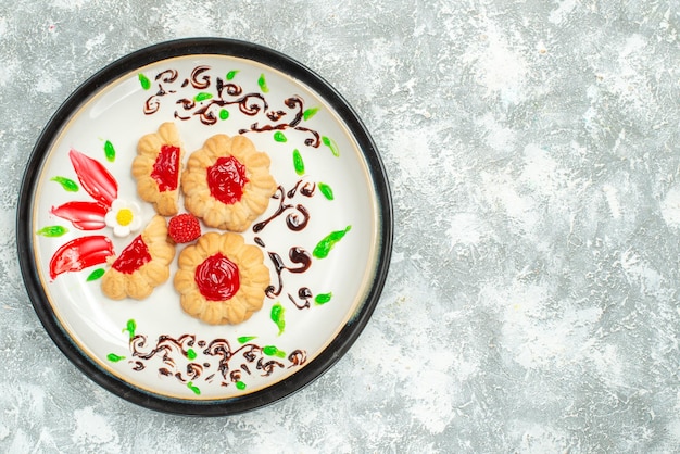 Free photo top view delicious cookies with red jelly inside plate on white background cake cookies sweet tea