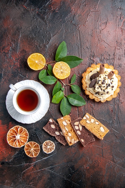 Free photo top view delicious creamy cake with cup of tea on a dark table sweet cake dessert