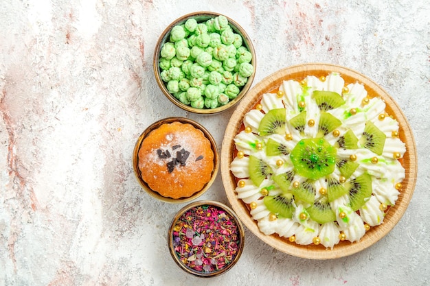 Top view delicious dessert with sliced kiwis and candies on white background dessert cream fruit cake candy