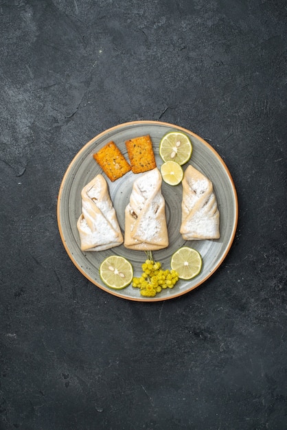 Free photo top view delicious dough with sugar powder and crackers on dark grey background pastry bake sugar sweet cake cookie