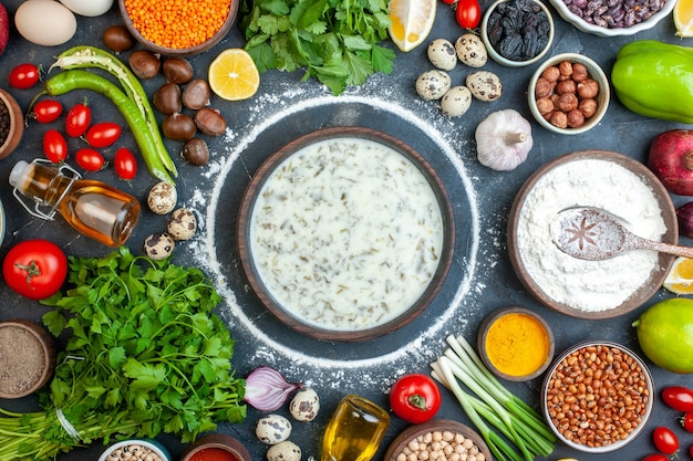 Top view delicious dovga in wooden bowl coriander cherry tomatoes quail eggs garlic flour in wooden bowl hot pepper on table