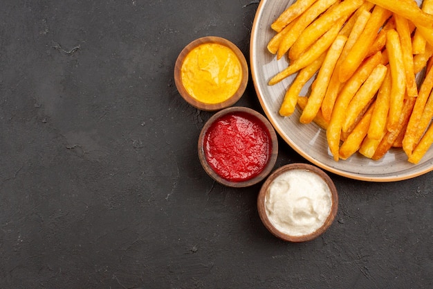 Top view delicious french fries with seasonings on a dark background dish potato meal fast-food burger