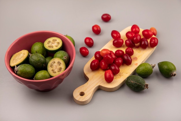 Top view of delicious fresh feijoas on a bowl with cornelian cherries on a wooden kitchen board on a grey wall