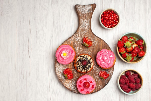 Top view delicious fruit cakes creamy desserts with berries and fruits on the white background cream tea sweet cookie dessert cake