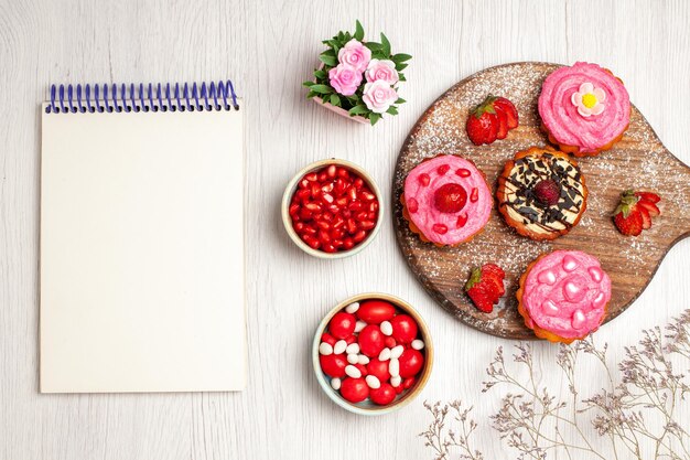 Top view delicious fruit cakes creamy desserts with candies and fruits on white background cream sweet cookie dessert cake tea