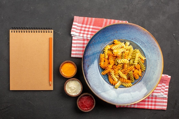 Free photo top view delicious italian pasta unusual cooked spiral pasta on a dark background pasta dish meal cooking dinner