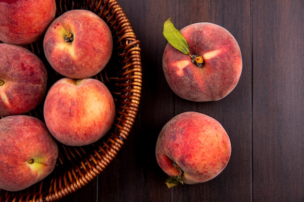 Top view of delicious and juicy peaches on bucket on wood