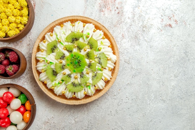 Top view delicious kiwi dessert with candies on light white background dessert cake cream fruit tropical