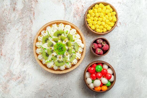 Top view delicious kiwi dessert with candies on a white background dessert cake cream fruit tropical