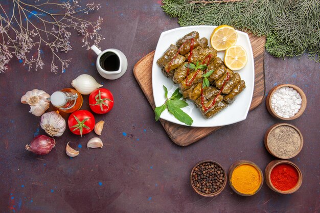 Top view delicious leaf dolma with fresh vegetables and seasonings on dark desk meal dish leaf meat dinner food