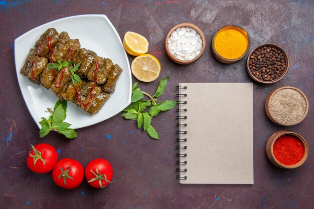 Top view delicious leaf dolma with lemon seasonings and tomatoes on the dark background dish leaf dinner food meat