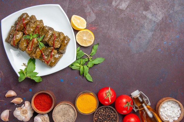 Top view delicious leaf dolma with lemon seasonings and tomatoes on a dark background dish leaf food meat dinner