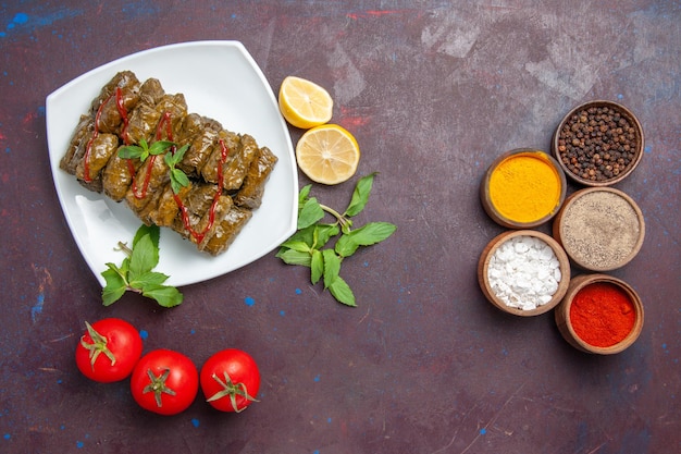 Top view delicious leaf dolma with lemon seasonings and tomatoes on dark desk dish leaf dinner food meat