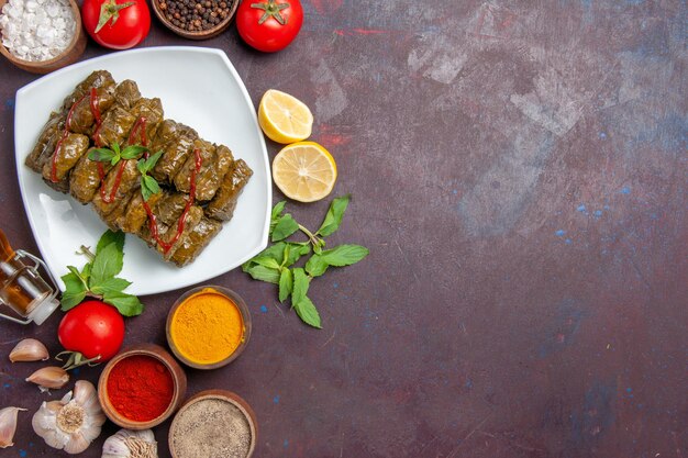 Top view delicious leaf dolma with seasonings and tomatoes on dark background dish leaf food meat dinner