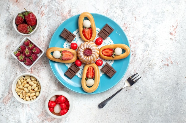 Free photo top view delicious little cake with chocolate bars and sweet crackers on a white background crackers sweet biscuit cake pie tea