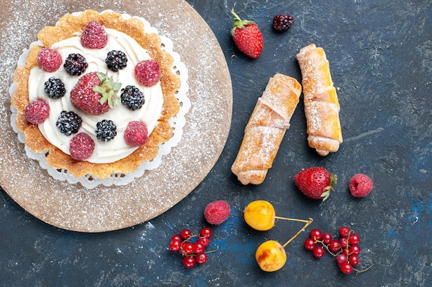 Free photo top view of delicious little cake with sugar powder cream and berries along with bangles on dark desk, berry fruit cake biscuit