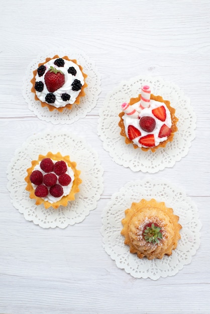 Free photo top view of delicious little cakes with cream and different berries on white, cake biscuit bake fruit sweet