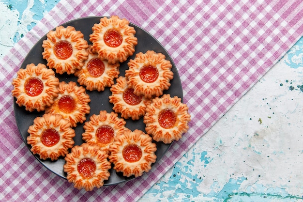 Top view delicious little cookies with orange jam on blue desk cookie biscuit sweet sugar color tea