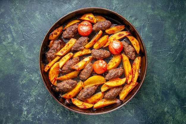 Top view of delicious meat cutlets baked with potatoes and tomatoes on green and black mix color background