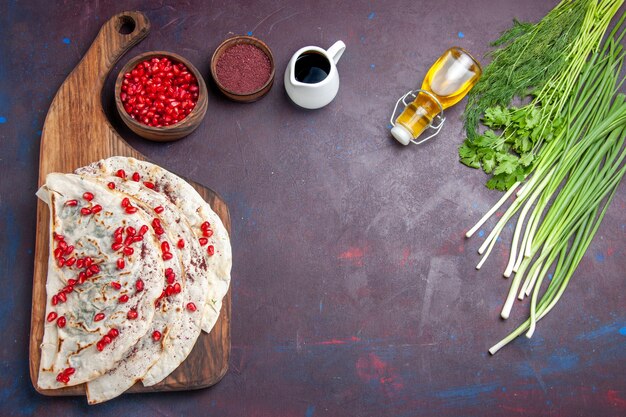 Top view delicious meat qutabs pitas with fresh red pomegranates on a dark background dough meal food pita