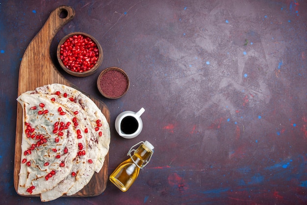 Top view delicious meat qutabs pitas with fresh red pomegranates on a dark desk dough meal food pita