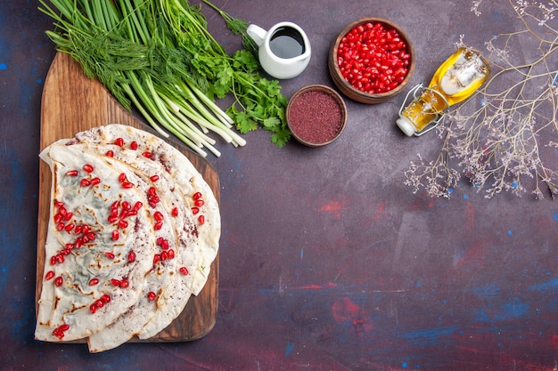 Top view delicious meat qutabs pitas with fresh red pomegranates on the dark surface dough meal food pita