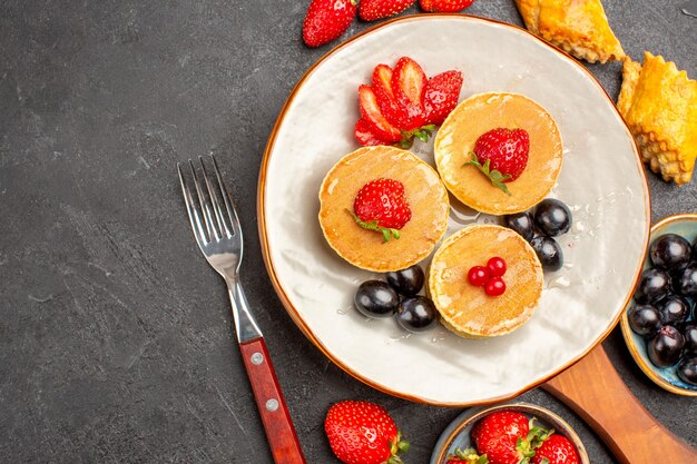 Top view delicious pancakes with fruits on a dark surface pie fruit cake sweet