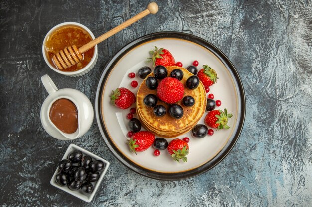 Top view delicious pancakes with honey and fruits on light surface cake sweet fruits