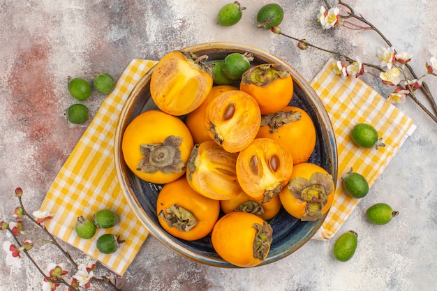 Top view delicious persimmons in a bowl on kitchen towel on nude background