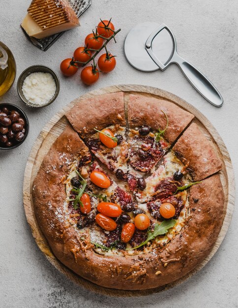 Top view of delicious pizza with tomatoes and cutter