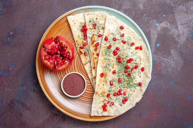 Top view delicious qutabs cooked dough pieces with greens and pomegranates on dark surface dough meal dinner cooking dish