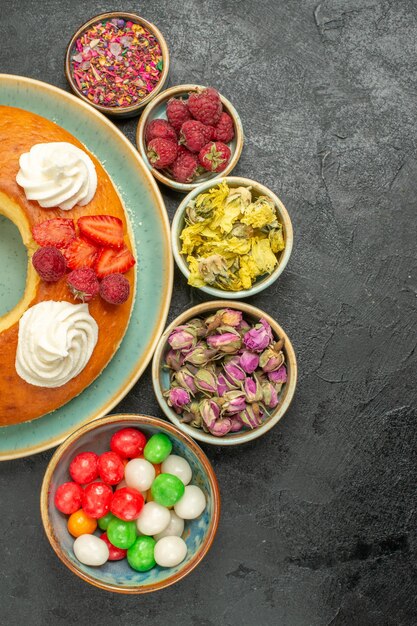 Top view delicious round pie with candies on grey background sugar cookies biscuit cake pie sweet tea