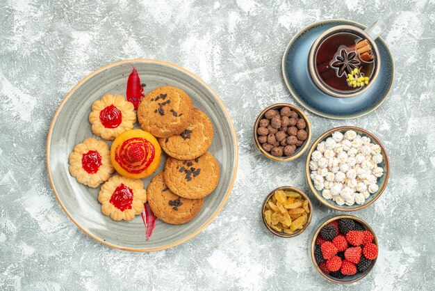 Top view delicious sand biscuits with cookies candies and cup of tea on white background tea sugar cookie sweet cake biscuit