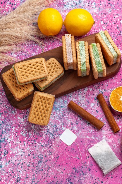 Top view delicious sandwich cookies with lemon and cinnamon on the pink desk.