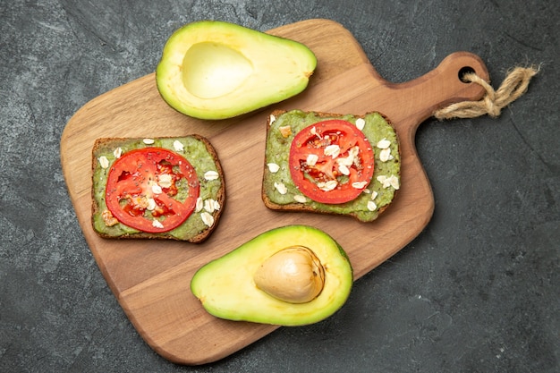 Top view delicious sandwiches with avocado and red tomatoes on a grey surface snack meal burger sandwich bread