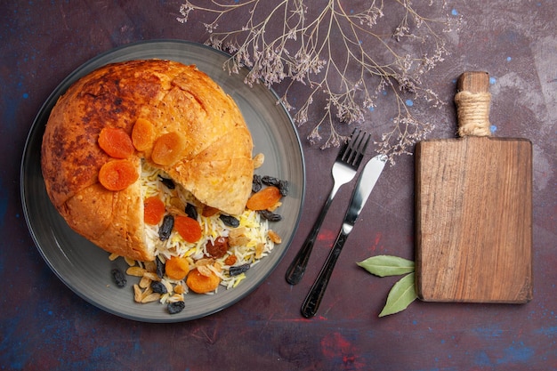 Top view of delicious shakh plov with raisins inside round dough on dark surface