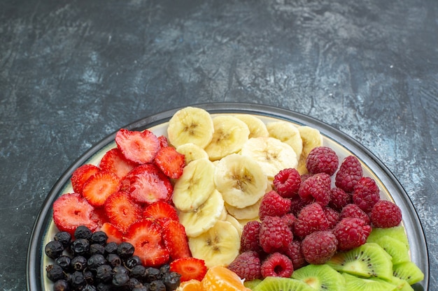 Free photo top view delicious sliced fruits inside plate on gray exotic color healthy life photo mellow tree ripe shade