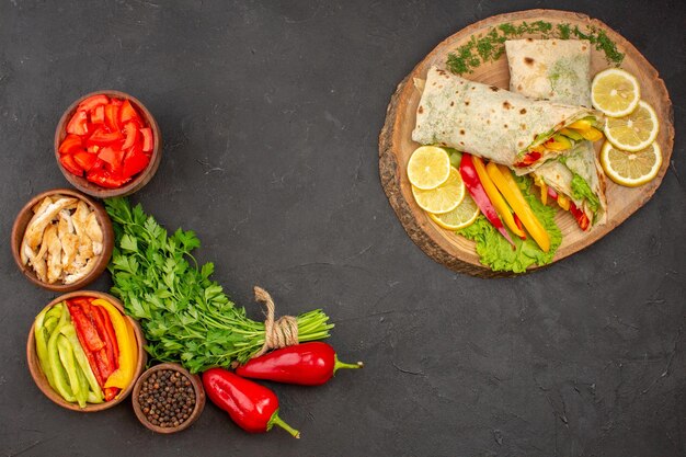 Top view delicious sliced shaurma meat sandwich with lemon and greens on a dark background burger sandwich ripe snack bread