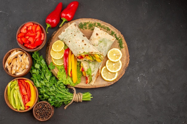 Top view delicious sliced shaurma meat sandwich with lemon and greens on dark background burger sandwich ripe snack bread