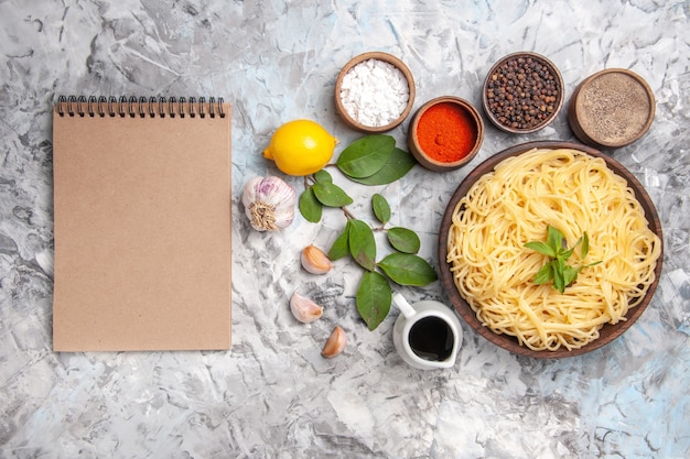 Free photo top view delicious spaghetti with seasonings on light white table dinner pasta dough meal