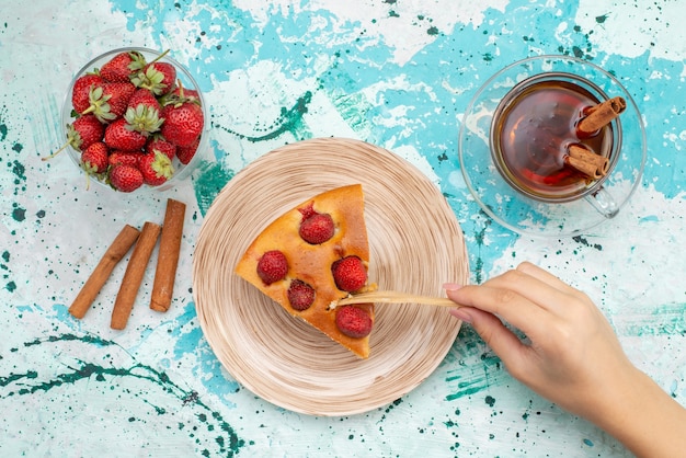 Free Photo top view of delicious strawberry cake sliced yummy cake with tea cinnamon fresh red strawberries on bright-blue desk, cake bake dough sweet