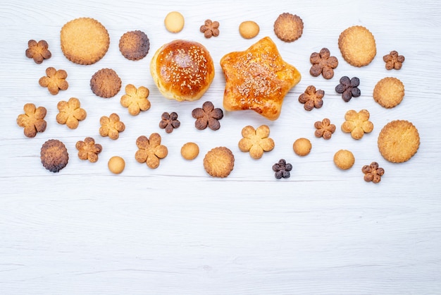 Top view of delicious sweet cookies different formed along with pastries on light desk, cookie biscuit sweet sugar