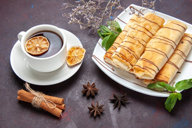 Top view delicious sweet pastries with cup of tea on dark space