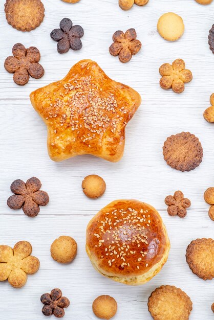 Top view of delicious sweet pastries with yummy cookies on light, pastry cookie biscuit sweet sugar