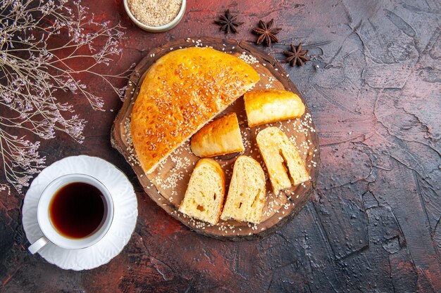 Top view delicious sweet pastry sliced in pieces with tea on dark surface