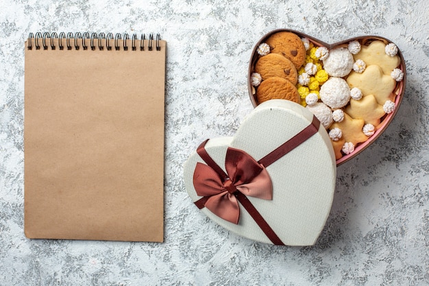 Free photo top view delicious sweets biscuits cookies and candies inside heart shaped box on white surface sugar cake pie sweet yummy